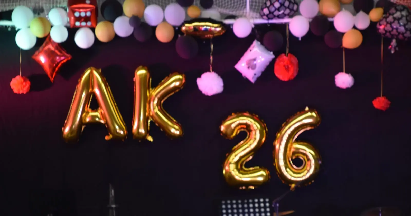 Bühnendekoration mit goldenem Ballonschriftzug „AK 26“, Luftballons und Pompons