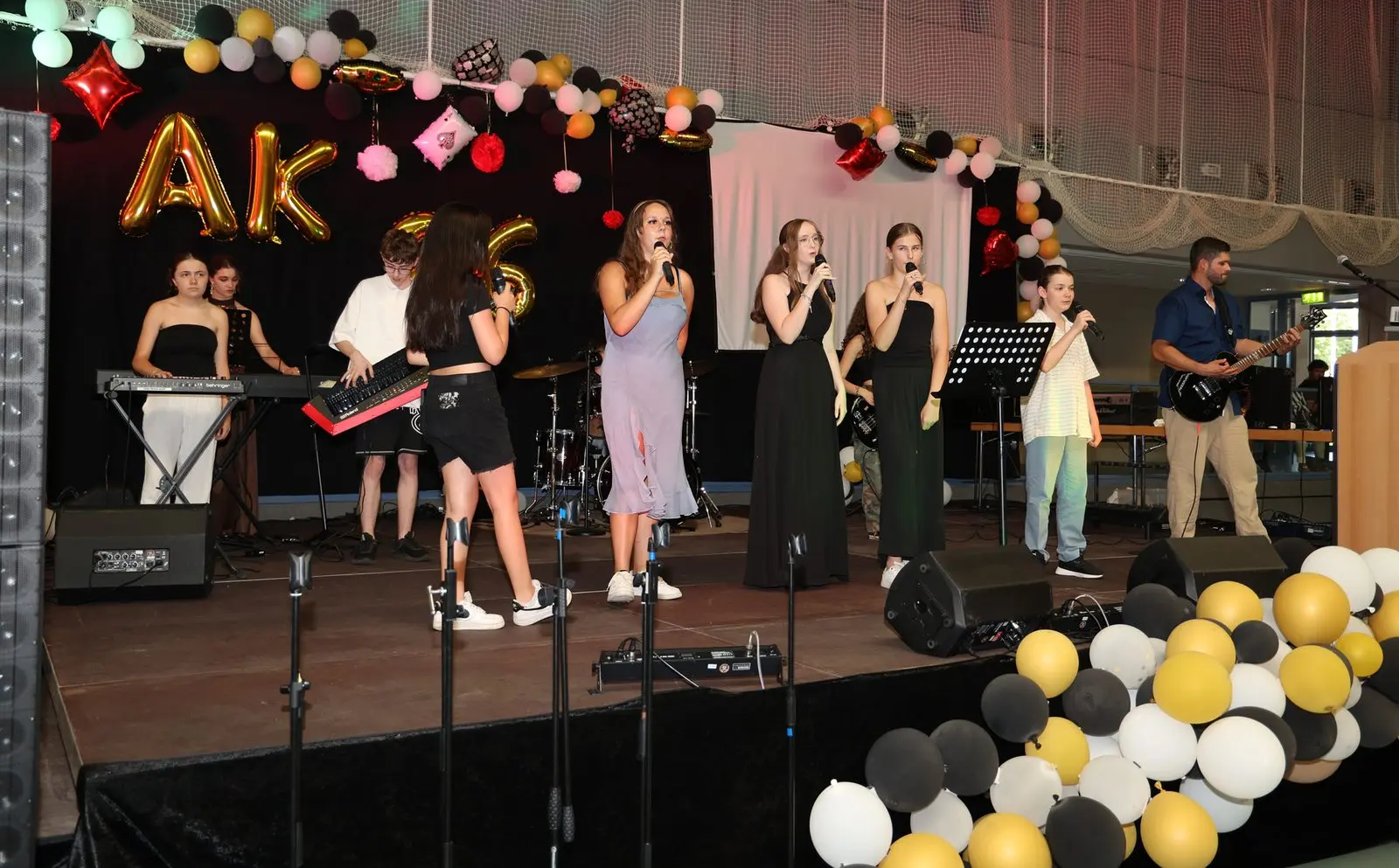 Schulband auf der Bühne mit Keyboards, mehreren Sängerinnen und einem Gitarristen