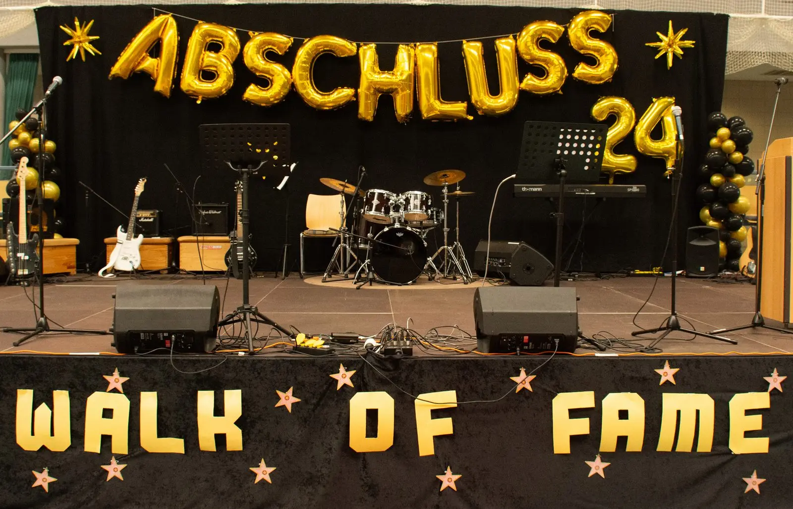 Geschmückte Bühne mit Instrumenten, Ballonschriftzug „ABSCHLUSS 24“ und Banner „WALK OF FAME“