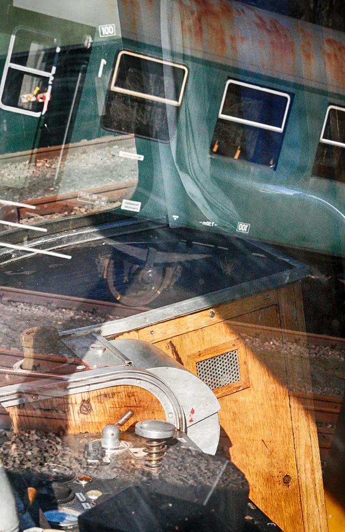 Fotografie mit Spiegelungen: alter Eisenbahnwagen und Maschinenteile in einer Glasscheibe