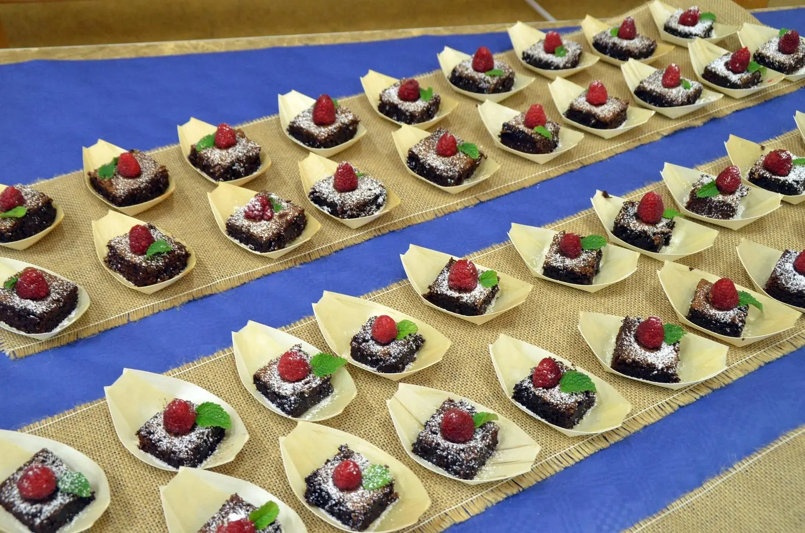 Tisch mit vielen kleinen Kuchenstücken in Pappschalen