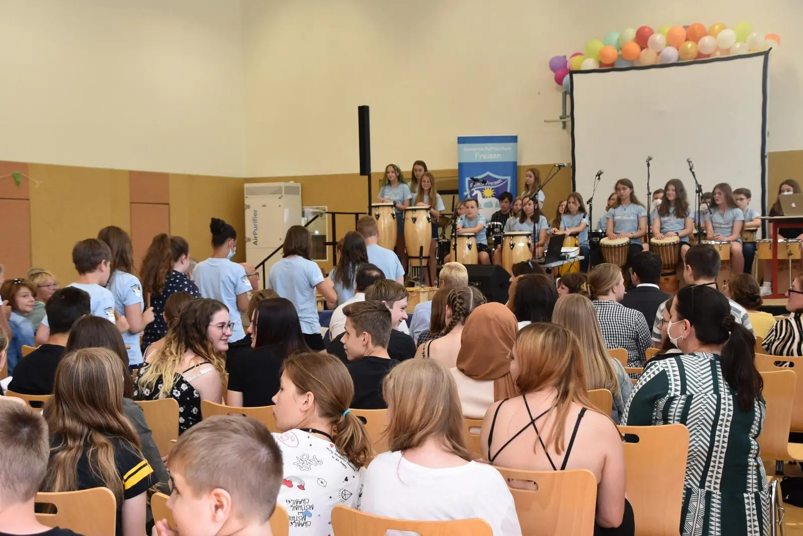Publikum in der Sporthalle, vorne die Musikklasse auf der Bühne