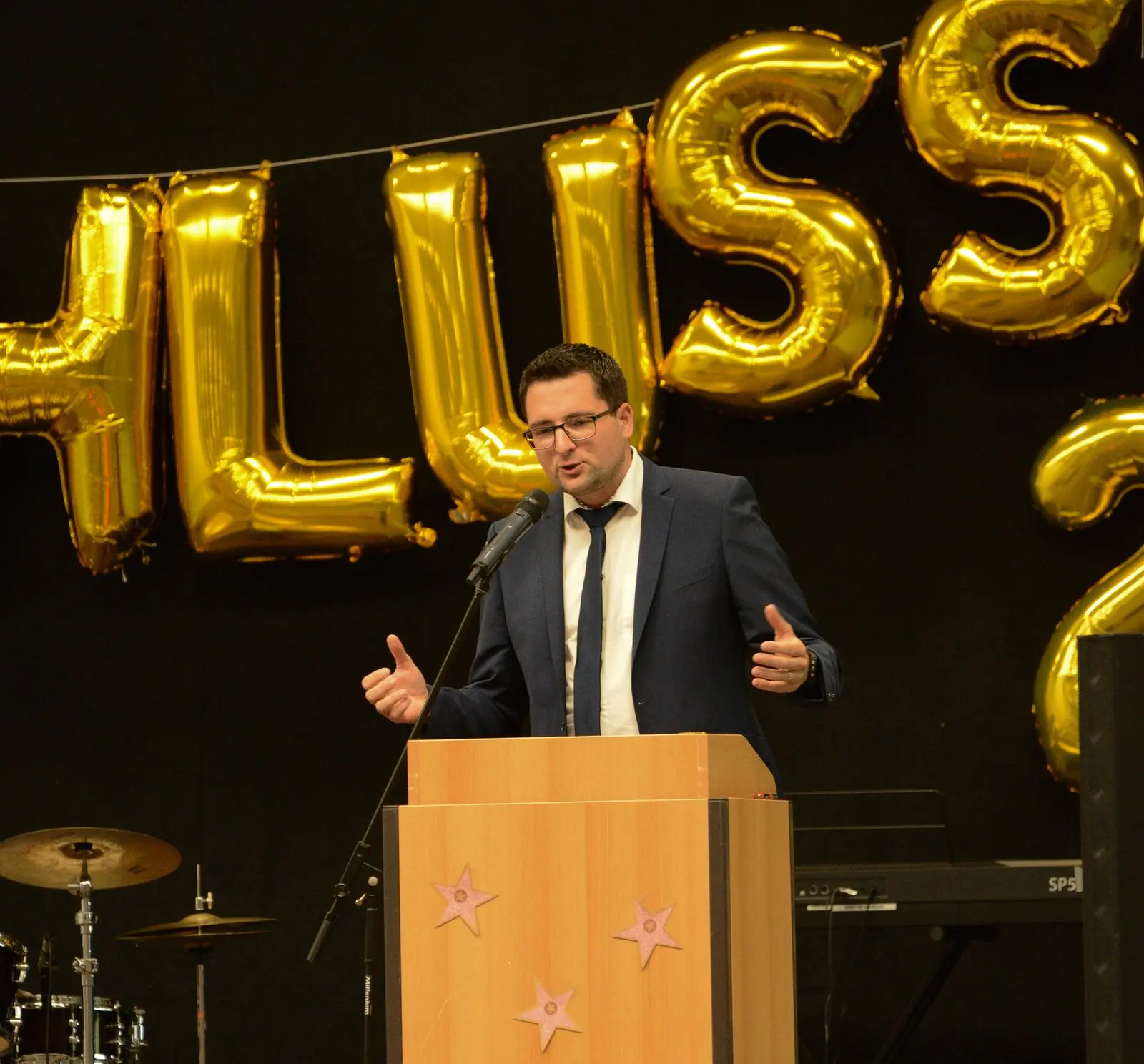 Ein Mann im dunklen Anzug mit Brille hält gestikulierend eine Rede am Rednerpult