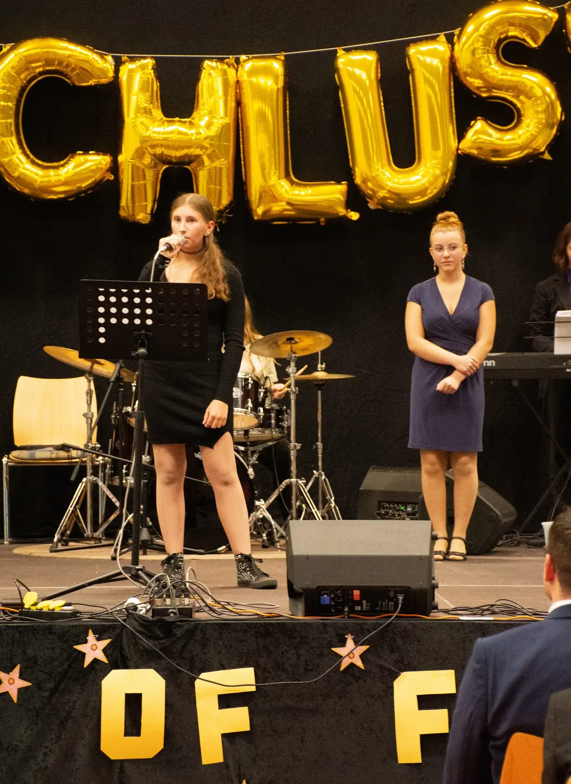 Eine Sängerin der Schulband singt am Notenständer, daneben steht eine weitere Schülerin