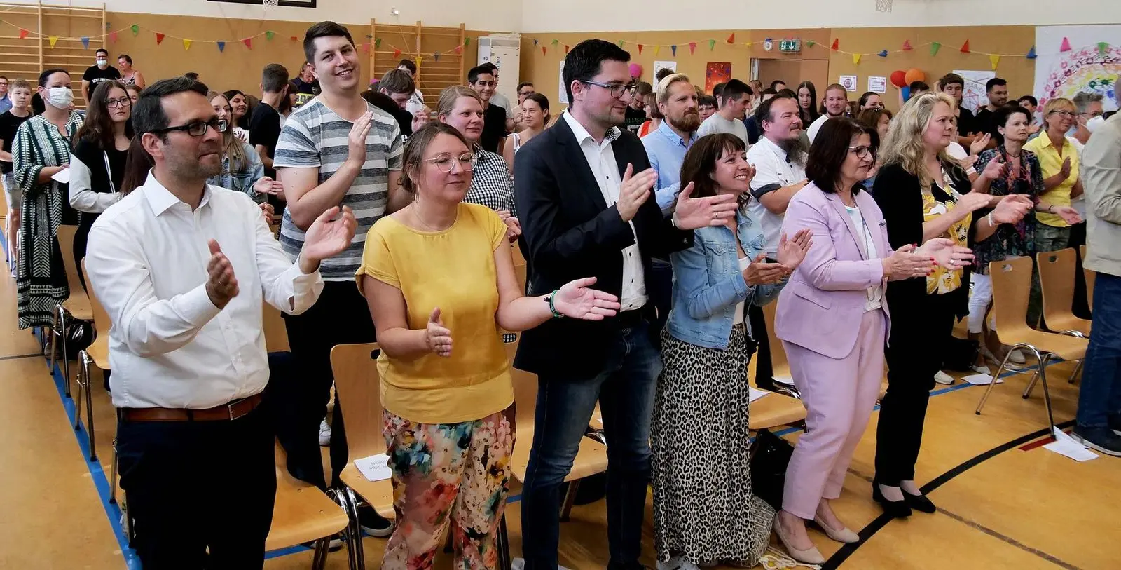 Gäste stehen und klatschen in der Sporthalle