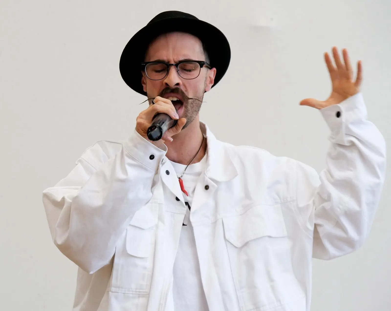 Sänger mit Hut und weißer Jacke singt ins Mikrofon