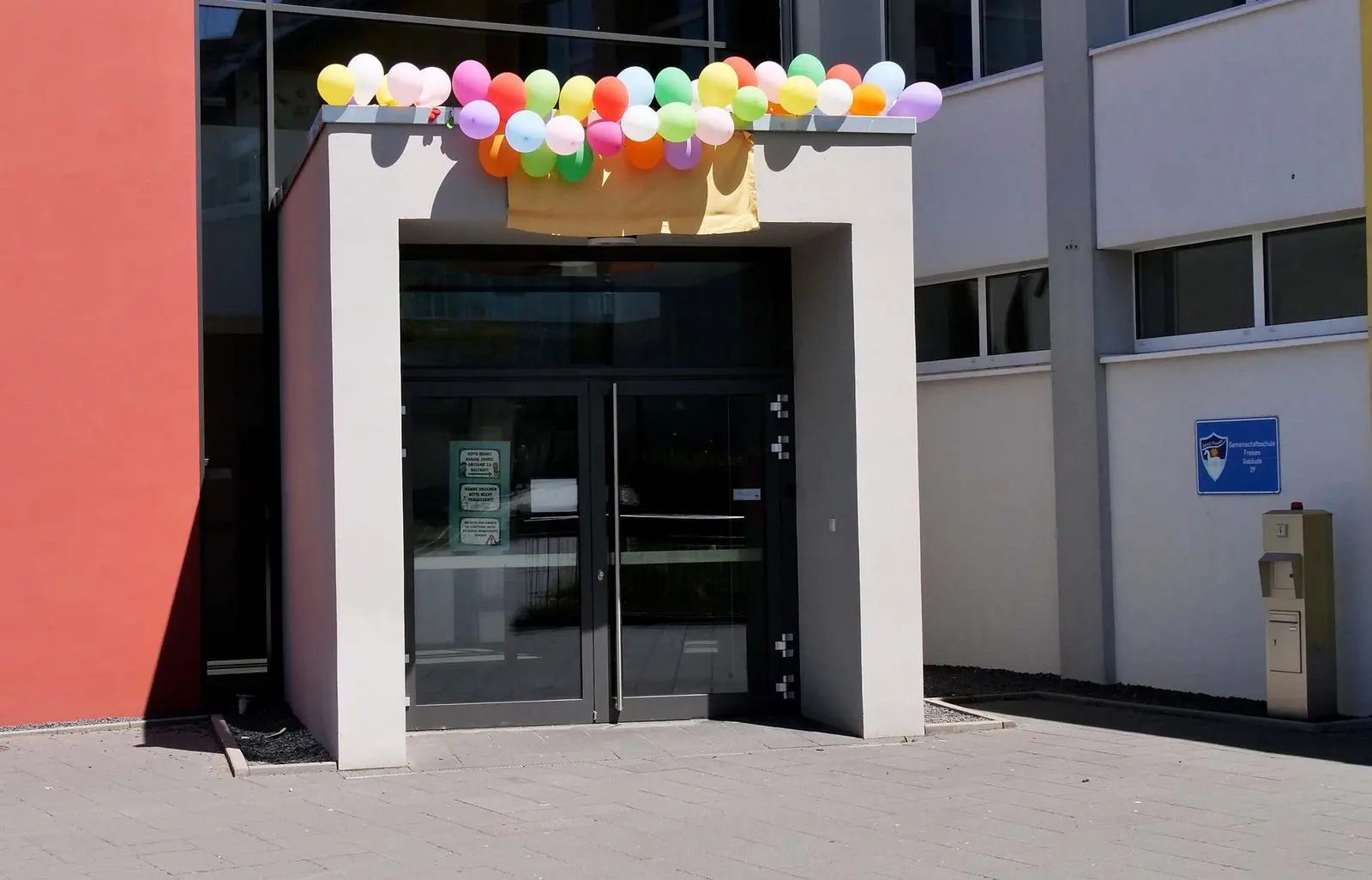 Schuleingang, über der Tür bunte Luftballons