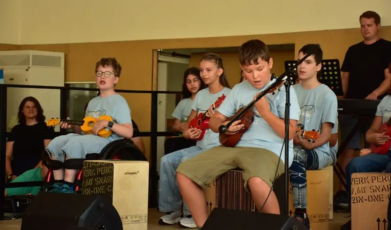 MusiKlasse spielt Ukulele, auf Cajóns sitzend, bei der Einschulungsfeier