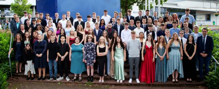 Großes Gruppenfoto der Abschlussschülerinnen und -schüler in festlicher Kleidung auf einer Treppe