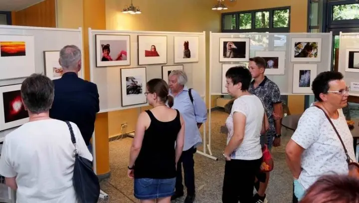 Besucherinnen und Besucher betrachten Fotos an Stellwänden der Ausstellung