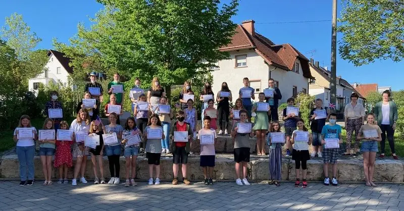 Große Gruppe von Schülerinnen und Schülern mit Urkunden auf Stufen im Freien