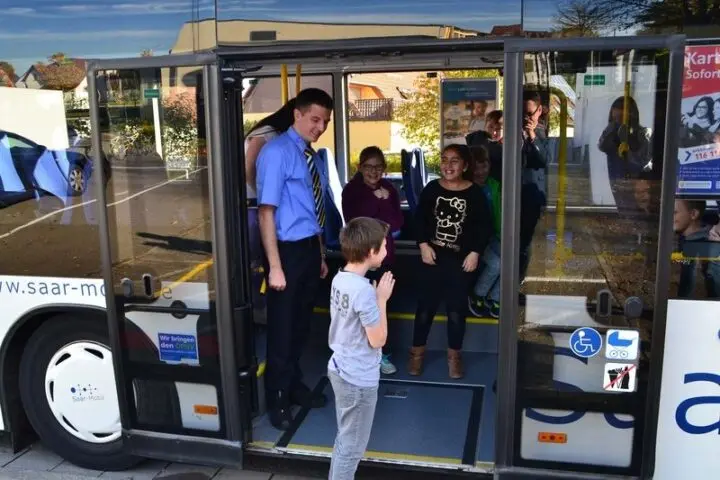 Busfahrer und Kinder in der geöffneten Tür eines Saar-Mobil-Busses