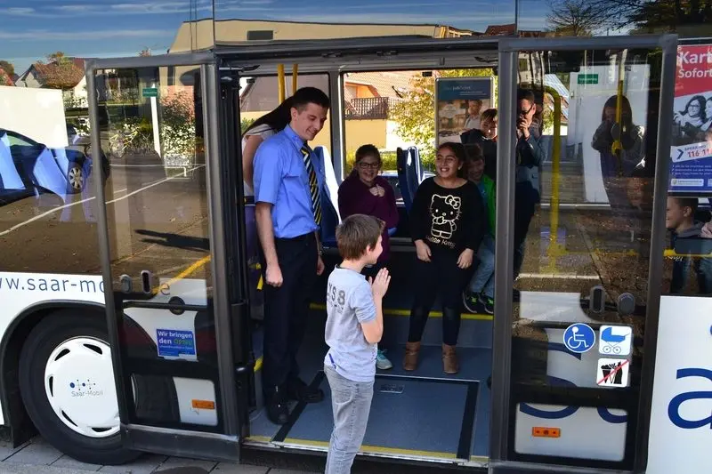 Busfahrer und Kinder in der geöffneten Tür eines Saar-Mobil-Busses