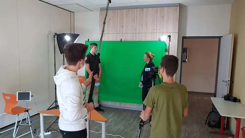 Jugendliche mit Kamera und Tonangel filmen ein Gespräch vor einem Greenscreen
