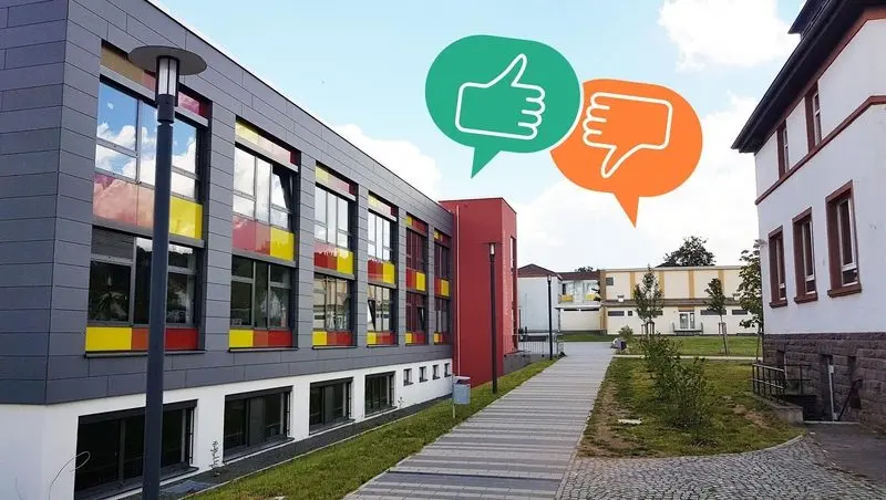 Schulgebäude mit bunten Fenstern, darüber Sprechblasen mit Daumen hoch und Daumen runter