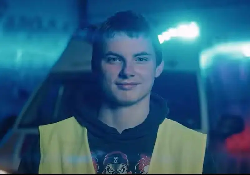 Lächelnder Jugendlicher in Warnweste vor einem Rettungswagen, Standbild aus dem Imagefilm