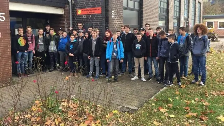 Gruppe von Jugendlichen vor dem Gebäude mit dem Schild „Ausbildungswerkstatt St. Wendel“