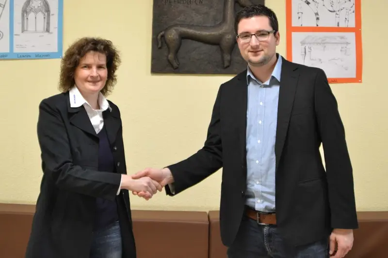 Eine Frau und ein Mann im Sakko geben sich die Hand