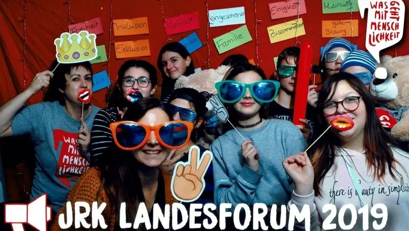 Fotobox-Bild: Jugendliche mit Spaßbrillen und Requisiten vor Wortkarten wie „Vielfalt“, Schriftzug „JRK Landesforum 2019“