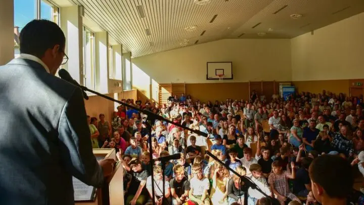 Blick vom Rednerpult in die voll besetzte Turnhalle mit Kindern und Eltern