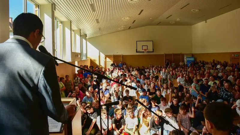 Blick vom Rednerpult in die voll besetzte Turnhalle mit Kindern und Eltern