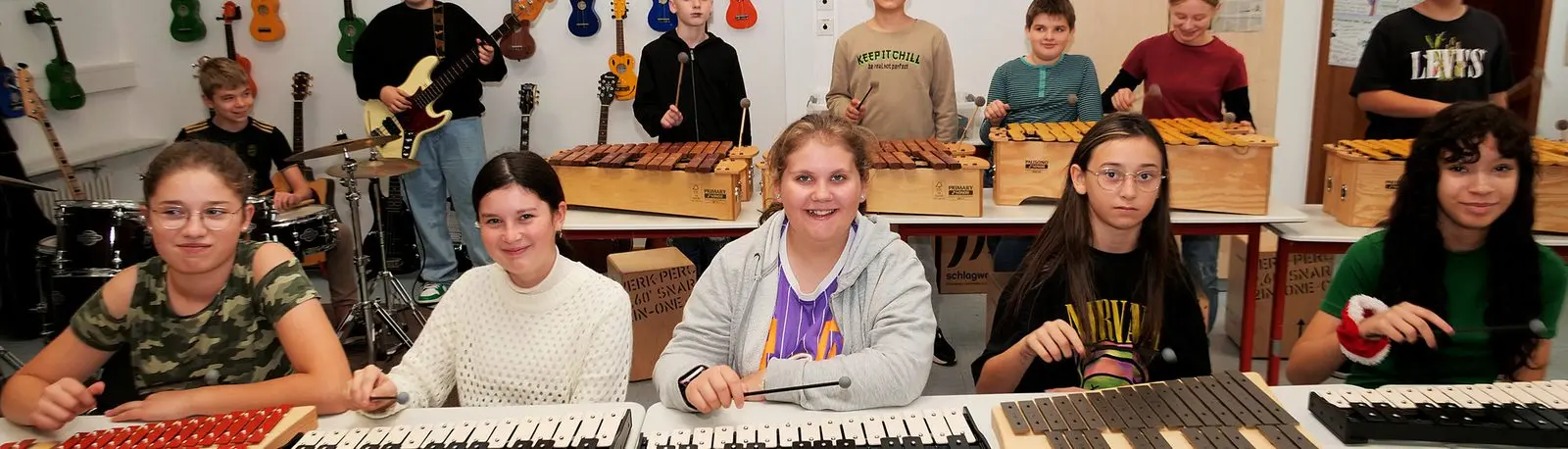 Schülerinnen und Schüler an Xylofonen und Metallofonen, im Hintergrund Gitarre und Schlagzeug