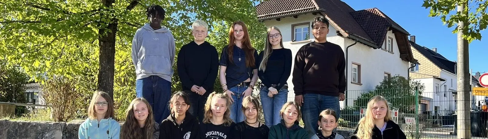 Breiter Ausschnitt des Gruppenfotos der Schülervertretung vor einem Baum und einem Wohnhaus