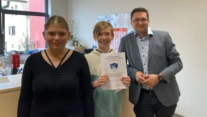 Schüler hält Urkunde „Schülervorbild des Monats September 2023“, neben ihm eine Schülerin und ein Erwachsener