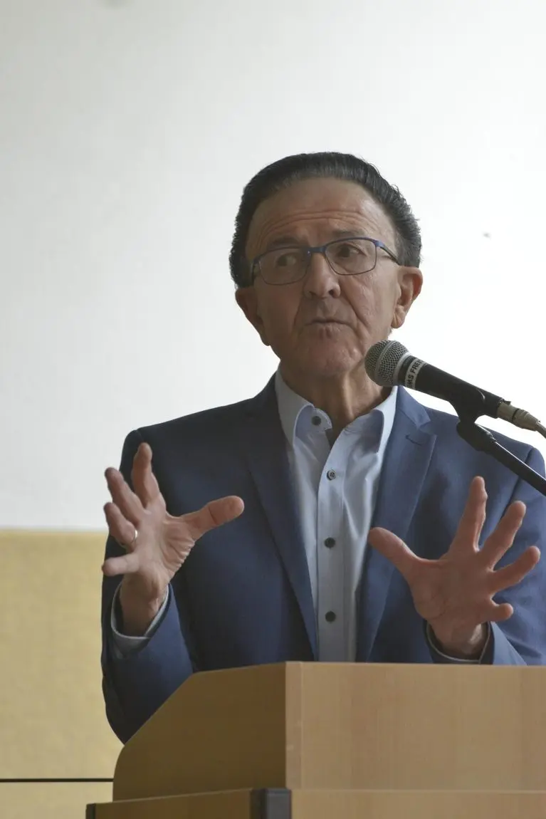 Älterer Mann im Sakko spricht gestikulierend am Rednerpult mit Mikrofon