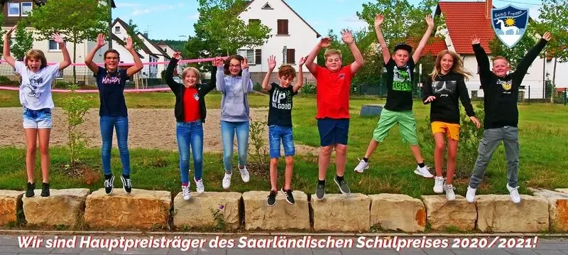 Jugendliche springen mit erhobenen Armen von einer Steinmauer, darunter Schriftzug zum Schulpreis