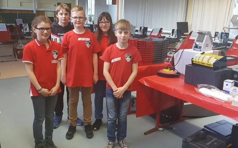 Fünf Schulsanis in roten Poloshirts im vorbereiteten Raum für die Blutspende