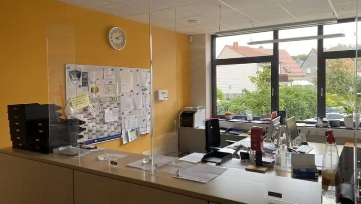 Sekretariat mit Plexiglas-Schutzwand am Tresen, Schreibtischen und Pinnwand