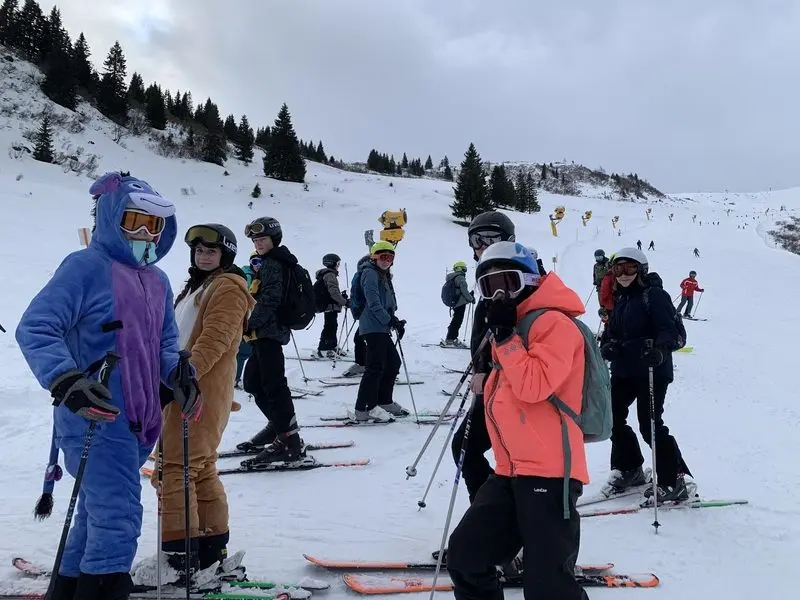 Skigruppe auf der Piste, vorne zwei Jugendliche in Tierkostümen