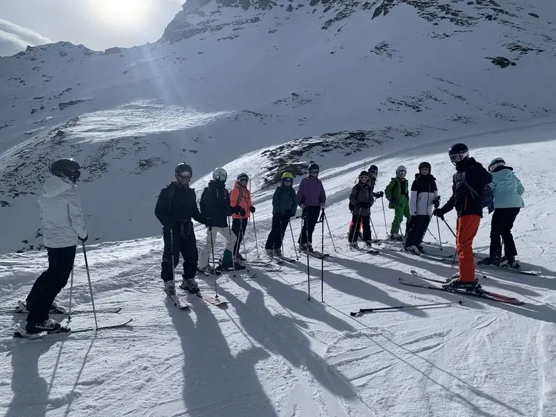 Skigruppe steht im Gegenlicht an einem sonnigen Hang