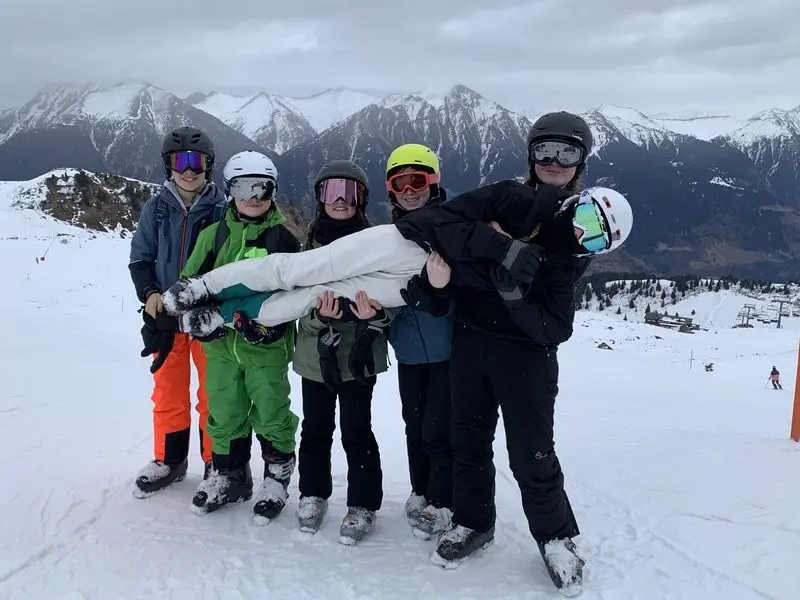 Fünf Jugendliche auf der Piste tragen eine weitere Person quer auf den Armen