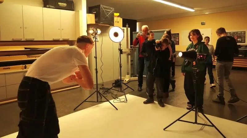 Foto-AG im Studio: Jugendlicher fotografiert mit Blitzlicht, andere sehen mit Kameras zu