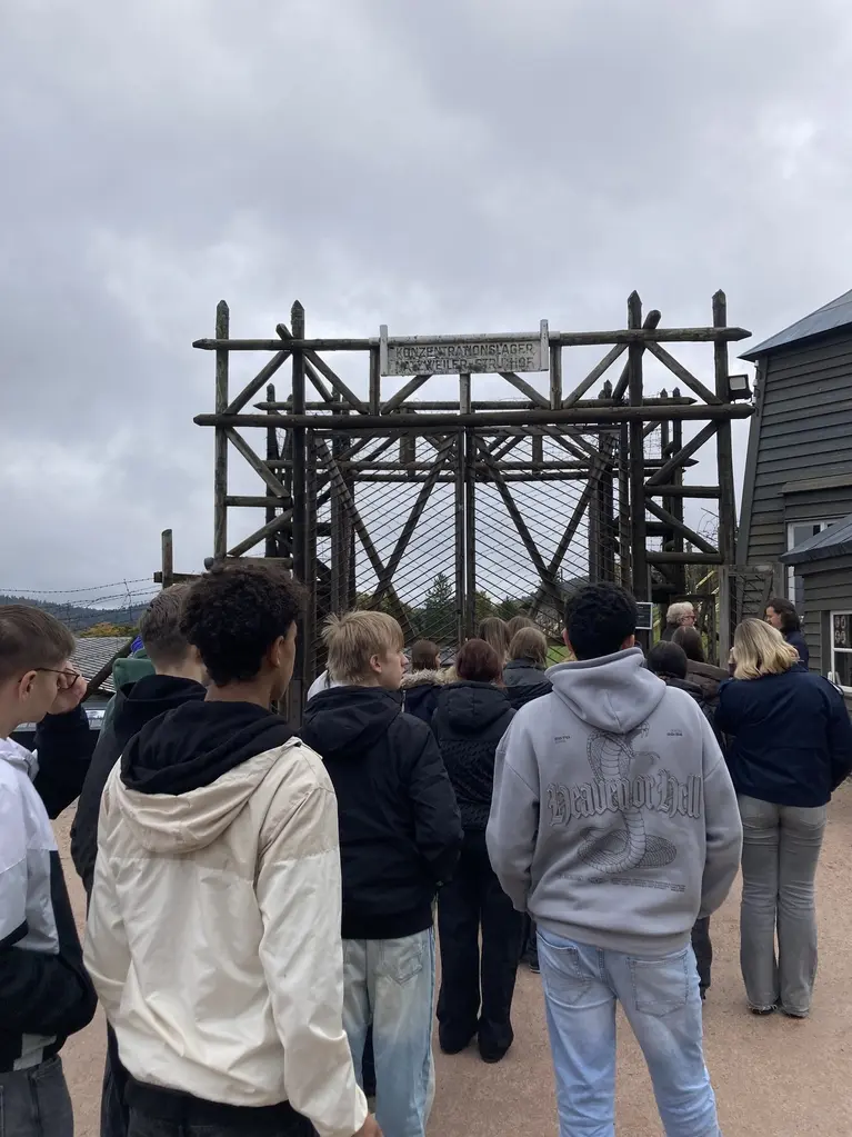 Gruppe Jugendlicher vor dem hölzernen Lagertor des ehemaligen Konzentrationslagers Natzweiler-Struthof