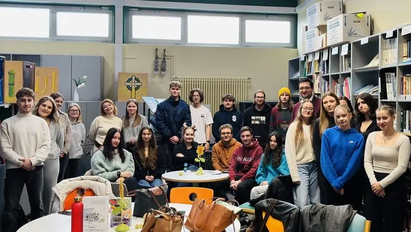 Gruppenfoto von Jugendlichen und Erwachsenen in einem Raum mit Bücherregalen